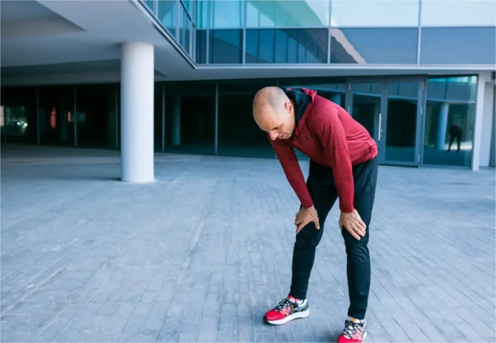 Exhausted male athlete standing outside the building