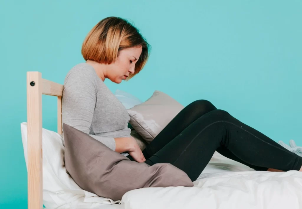 Woman touching hurting belly on bed