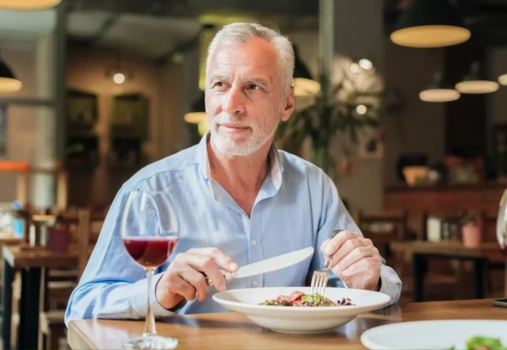 Medium shot old man having a meal at restaurant